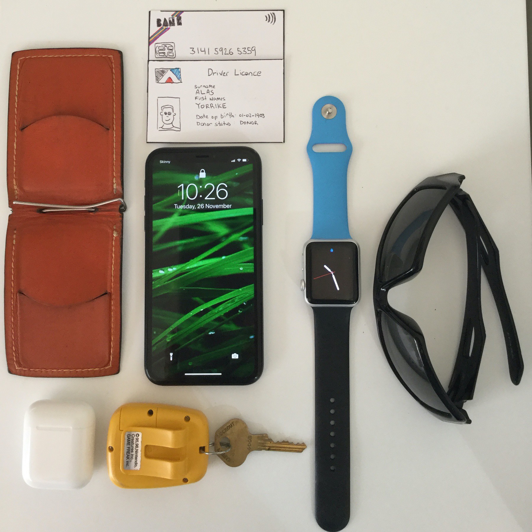 A picture of my thin wallet, phone, keys, airpods, sunglasses and cards I carry around daily.