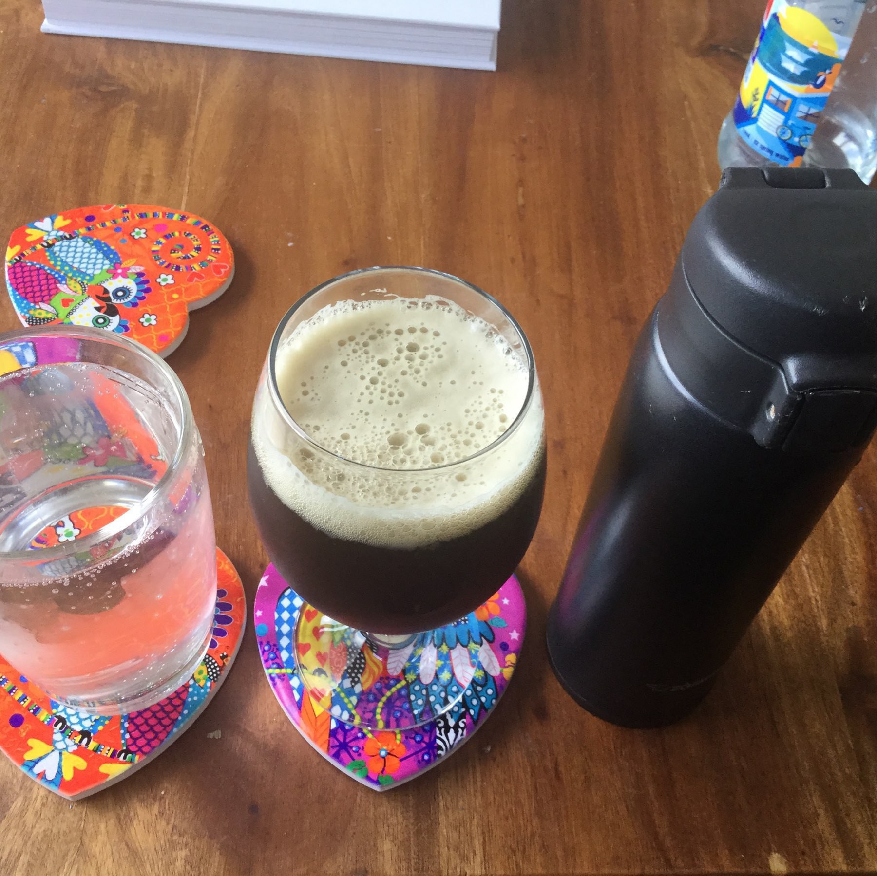 A glass of sparkling water, a glass of beer and a thermos of coffee. 