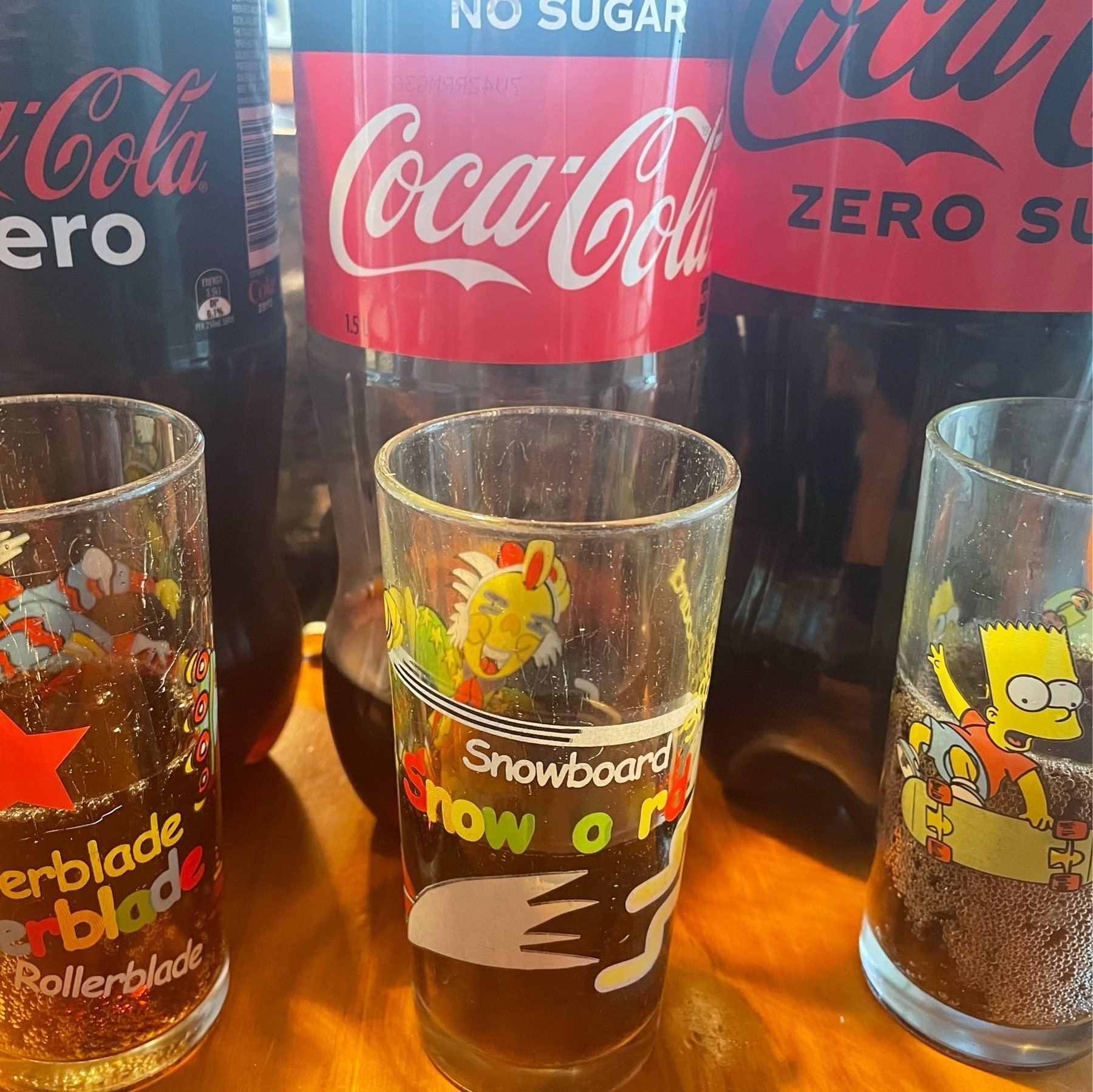 From left to right, a bottle of Coke Zero, Coke No Sugar and Coke Zero Sugar. each bottle has a small glass in front if it with a sample in it. 