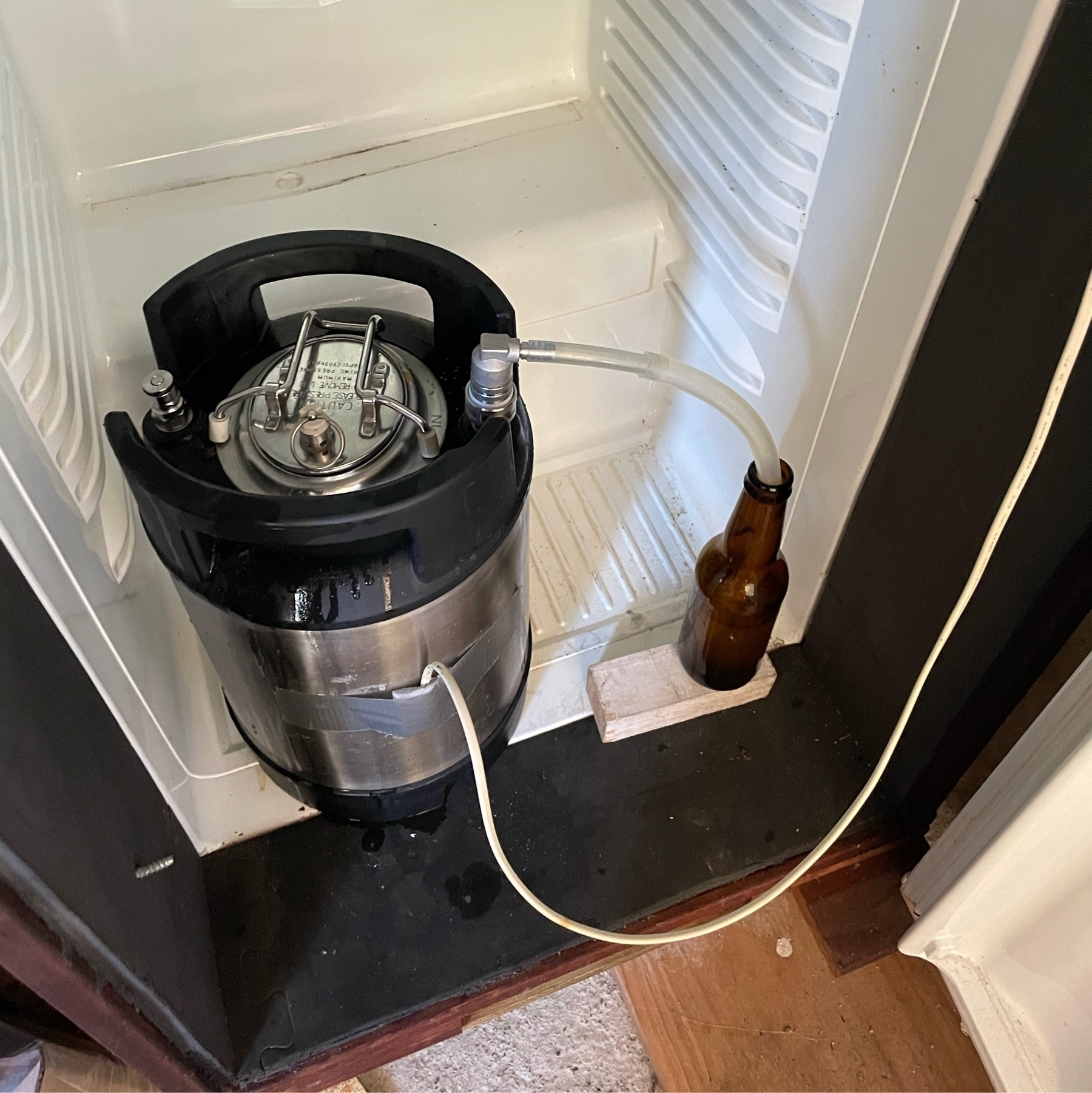 A 9 litre keg I use as a fermentor, sitting in my fermentation fridge. an outlet is connected by a tube to a bottle of sanitiser to allow CO₂ to escape but nothing nasty to get in. 